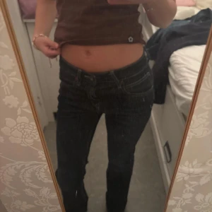Mörkblå bootcut jeans från Lee - Säljer ett par mörkblå jeans från Lee med klassisk bootcut-passform och låg midja. Jeansen har tydliga kontrastsömmar, fem fickor och Lee-lapp bak i midjan. Perfekta för dig som gillar en tidlös och snygg look.