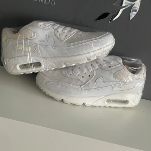 Nike Air Max 90  - Fräscha Nike Air Max 90 i helvitt, klassisk chunky siluett med mesh och skinnpaneler. Snygga detaljer som synlig Air Max-dämpning i sulan och diskret logga på sidan. Perfekta för dig som gillar cleana sneakers med sportig vibe.