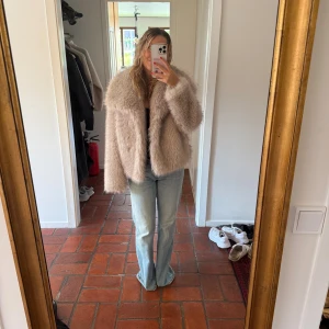 Pälsjacka  - Säljer en supermjuk och fluffig beige pälsjacka med bred krage och lång ärm. Jackan har en oversized passform och är perfekt för dig som vill sticka ut med en trendig look. Materialet är fuskpäls och jackan är helfärgad utan mönster.