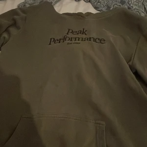 Grå hoodie från Peak Performance - Säljer en grå hoodie från Peak Performance med broderad logga på bröstet. Tröjan har huva och en stor magficka framtill. Perfekt för dig som gillar en enkel och stilren look. Mjuk insida och klassisk passform. Stl 170. Pris kan diskuteras 