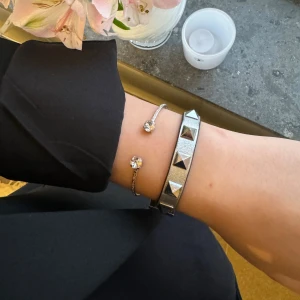 Valentino armband - Valentino armband, köpt på Valentinos egna hemsida sommaren 2024. Armbandet är i bra skick, det är lite slitet vid änden av armbandet men det är inget som är speciellt märkbart (därav säljer jag för billigt pris). Boxen medföljer och även en extra nit till armbandet medkommer. Kontakta för fler frågor/bilder! Köpt för 3000+ kr