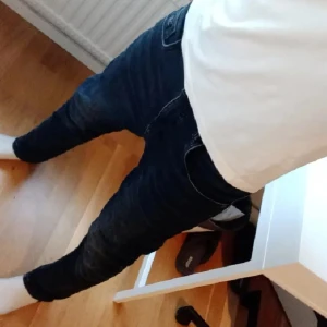 Mörkblå slim jeans - Snygga mörkblå jeans med slim passform och klassisk femficksdesign. Jeansen har en smal siluett och är tillverkade i stretchigt denim som sitter tajt längs benen. Perfekta för dig som gillar en modern och stilren look.