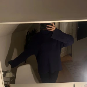 Mörkblå stickad polotröja - Säljer en mörkblå stickad polotröja med oversized passform och långa ärmar. Tröjan har en hög krage som ger en chill vibe och är perfekt för kalla dagar. Enkel och stilren design som funkar till många olika outfits.