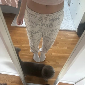 Vita mjukisbyxor med grått graffiti-mönster - Säljer ett par vita mjukisbyxor med grått graffiti-inspirerat mönster. Byxorna har resår i midjan och snörning för extra komfort. De är loose fit och perfekta för chill dagar hemma eller en coolare street style look. Materialet är mjukt och skönt och håller än varm.
