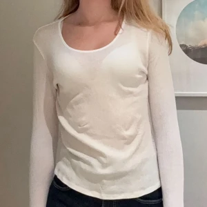 Topp från Weekday - Säljer en enkel och stilren vit långärmad topp med rundad halsringning. Modellen är figurnära och har en mjuk, tunn känsla som passar perfekt till jeans eller kjol. Materialet känns lätt och bekvämt mot huden. Från weekday, knappt använd! 