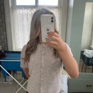 Beige stickad blus med pärlknappar 157 - Supersöt beige stickad blus från 157 med korta ärmar och pärlknappar hela vägen framtill. Mjuk och mysig. Använt en gång 