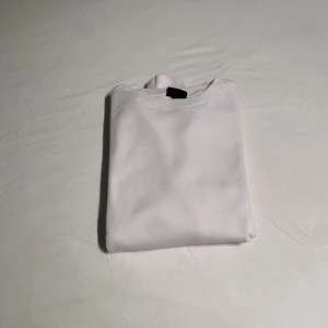 Vit sweatshirt i bomull, strl S - Enkel och stilren vit sweatshirt från H&M i storlek S. Tröjan har rund hals, ribbade muddar och är tillverkad i mjuk bomull. Perfekt för en clean och avslappnad look. Liten grön fläck på armen