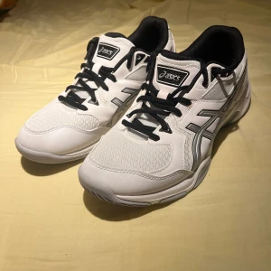 ASICS Gel-Rocket vita träningskor för sport  - Säljer ett par fräscha vita ASICS Gel-Rocket sneakers. De är i nyskick och det finns inga märken på användning. Skorna är väldigt stabila och är väldigt bekväma. Skorna är främst till för sporter som tennis, innebandy, badminton o.s.v. De funkar även suveränt till andra aktiviteter som spring och i gymet. Skorna har meshpartier för bra andningsförmåga och en slitstark sula med bra grepp. Perfekta för dig som gillar sportig stil och vill ha bekväma skor till träning eller vardag.