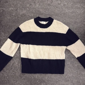 Randig ribbstickad tröja från H&M - Superfin ribbstickad tröja från H&M i XS med breda marinblå och beige ränder. Tröjan har rund halsringning och långa ärmar, perfekt för lager på lager under kyliga dagar.