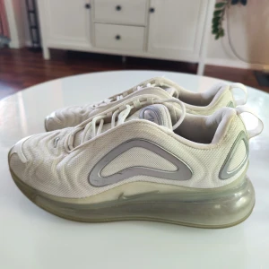 Nike Air Max 720 i beige, stl 38.5 - Nike Air Max 720 sneakers i beige med futuristisk design och genomskinlig, hög sula. Ovandel i mesh med vågigt mönster och silvriga detaljer. Skorna har snörning och en riktigt chunky plattformssula som ger extra höjd och streetkänsla.