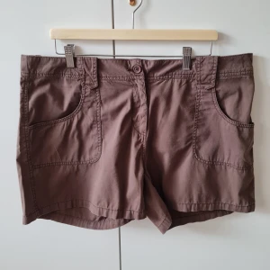 Shorts från N.Y. Near You strl XL (dam) - Snygga bruna shorts från N.Y. Near You med stora framfickor och bakfickor med lock och knapp. Klassisk passform med bälteshällor och knappstängning framtill. Perfekta för varma dagar! Storlek XL. Kan hämtas i Vallentuna.