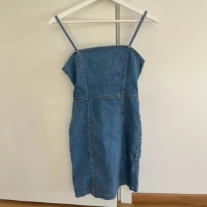 Blå jeansklänning - En blå jeans klänning med dragkedja i strl Xs (men passar som en S då den är väldigt stretchig). Knappt använd och mycket bra skick!