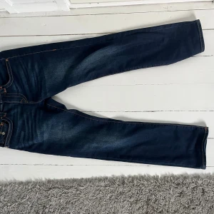 En par jeans från true religion - Ett par mörk blåa jeans från true religion. Feta jeans som passar till de mesta, jeansen gör att du sticker ut lite bland alla med en par unika bak fickor!!🤩🤩