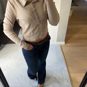 Beige croppad långärmad polotopp - Säljer en beige croppad polotopp med lång ärm och klassisk krage. 