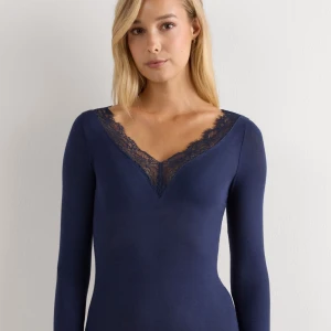 Marinblå topp med spetsdetaljer - Snygg marinblå långärmad topp med v-ringad hals och dekorativa spetsdetaljer både vid halsringningen och ärmsluten. Tunn och mjuk kvalitet som sitter skönt mot kroppen. Perfekt för dig som gillar stilrena plagg med en feminin touch.