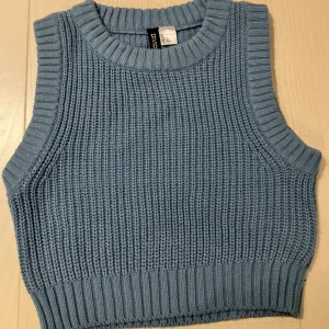 Ljusblå stickad väst från DIVIDED - Säljer en ljusblå stickad väst från DIVIDED i storlek XS. Västen har ribbade kanter vid hals och ärmslut samt en grovstickad struktur 