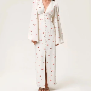 Vit långklänning Positano från Adoore - Superfin vit långklänning från Adoore i modellen Positano. Klänningen har röda blommiga detaljer, djup v-ringning, långa vida ärmar och knappar framtill. Sitter snyggt i midjan och har en slits framtill. Perfekt för sommarens alla tillfällen! Priset går att diskuteras! 😁