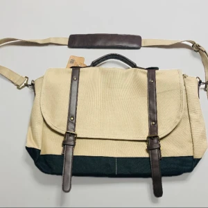 Beige datorväska Helt ny! 89kr ! - Stilren datorväska i beige canvas med mörkbruna detaljer i skinnimitation. Väskan har justerbar axelrem, handtag och två spännen framtill. Insidan har flera fack för laptop och tillbehör. Perfekt för plugget eller jobbet när du vill ha en clean look.