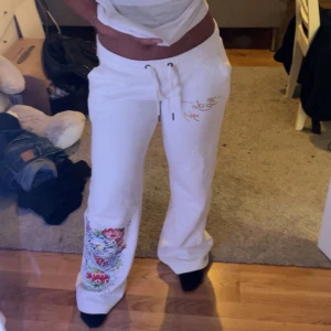 Lågmidjad Ed hardy mjukisbyxor  - Vita lågmidjad mjukisbyxor från Ed Hardy med guldig logga på baksidan och framtill. Byxorna har en stor färgglad tiger med blommor tryckt på ena benet. Passar mig som brukar ha xs men är lite för långa för mig som är 158 💕lägg gärna bud💕