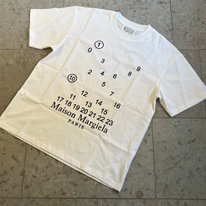 Vit Maison Margiela T-shirt  - Vit t-shirt från MM6 med ikoniskt svart sifferprint och logga på bröstet. Storlek M och oanvänt skick, fraktar inom 24h✅ vid mer frågor hör bara av er🏌️