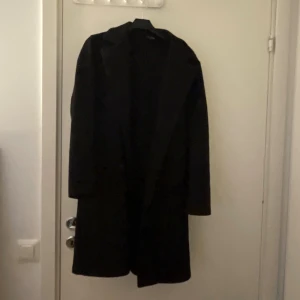 Svart lång kappa  - Svart lång kappa i storlek s med band runt midjan knappt använd därför den säljs.