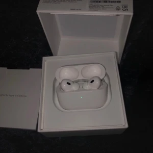 AirPods Pro (2nd generation) - Apple AirPods Pro (2nd generation) i nyskick med originalförpackning och extra öronkuddar. Trådlösa hörlurar med aktiv brusreducering, transparensläge och laddningsetui. Allt tillbehör medföljer och produkten ser oanvänd ut, inga synliga defekter eller slitage.