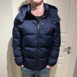 Ralph Lauren jacka - Säljer en skön Ralph Lauren jacka! | Mycket fint skick inga hål eller liknande, kan känna på ryggen att dunet klumpat sig lite på ett ställe men absolut inget som syns vilket du kan se på sista bilden! | Storlek XL 18/20 motsvarar en XS eller mindre S, modell 178cm! | Ställ gärna frågor innan du köper!