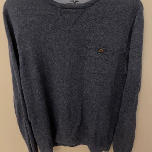 Mörkblå tröja från Hampton Republic - Mysig mörkblå tröja från Hampton Republic med rund halsringning och en liten bröstficka med knappdetalj. Tröjan har långa ärmar och är perfekt för lager-på-lager-stil under kyligare dagar.