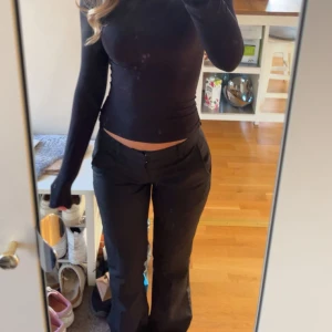 Svarta kostymbyxor med bootcut - Snygga svarta kostymbyxor med bootcut-snitt och låg midja. Byxorna har klassisk passform och är perfekta för en stilren look. Tillverkade i ett mjukt och bekvämt tyg som ger en dressad känsla.