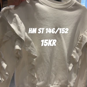 Vit volangtröja från H&M - Supersöt vit tröja från H&M med volangdetaljer längs ärmarna. Tröjan har rund halsringning och är långärmad, perfekt för dig som gillar en stilren men ändå lekfull look.