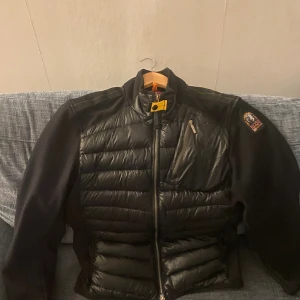 Svart pufferjacka Parajumpers M - Säljer en svart pufferjacka från Parajumpers i storlek M. Jackan har quiltad framsida och rygg, dragkedja framtill, bröstficka med dragkedja och klassisk PJS-patch på ärmen. Snygga detaljer med gul rem vid kragen och sportig känsla. Pris kan diskuteras!