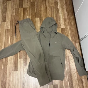 Nike tracksuit - Säljer en Nike tracksuit i färgen beige. Köpt på JD sports och vid intresse kan jag skicka fler bilder samt pris diskuteras. Lite blött på jackan för att den är nytvättad och inte hunnit torka ännu.  2 bilder visar 2 små små svarta fläckar som är knappt synliga… vill vara ärlig vid förhandling. 
