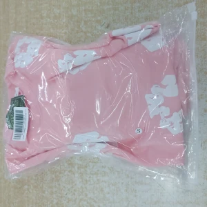 Denim tears S - Säljer en rosa t-shirt i storlek S med stora vita blommönster över hela plagget. T-shirten har klassisk passform och är tillverkad i mjukt material, perfekt för en chill och trendig look.