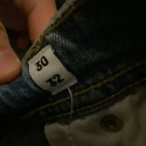 Ljusblå jeansbyxor i storlek 30/32 - Säljer ett par ljusblå jeansbyxor med klassisk passform och snygga slitningar. Jeansen har gul kontrastsöm och traditionell knappstängning. Perfekta för dig som gillar en enkel och stilren look. Kan gå ner i pris vid snabb affär 