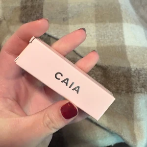 CAIA Lip Oil Vacay  - Superfräsch lip oil från CAIA i nyansen Vacay. Kommer i en snygg ljusrosa förpackning med silvrig logga. Oljan har en glansig, persikofärgad ton med skimmer och kommer med en mjuk applikator. Perfekt för att ge läpparna extra glow och fukt.