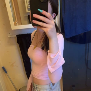 Ljusrosa offshoulder croppad topp från Gina tricot  - Säljer en ljusrosa offshoulder topp med croppad passform  och långa ärmar i xs. Toppen har en snygg, tight siluett och sitter skönt mot kroppen. Perfekt för dig som gillar trendiga och feminina plagg.