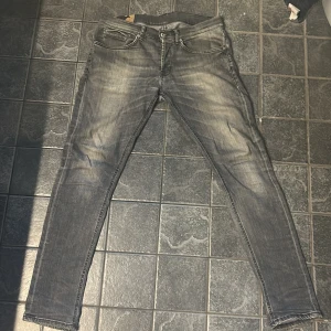  Dondup george stl 33 - Snygga grå jeans från dondup i storlek 33 med slitna detaljer och klassisk femficksdesign. Jeansen har smal passform och diskret tvättad look, perfekta för en avslappnad stil. Materialet är mjukt och stretchigt jeans för extra komfort. Har gått sönder i skrevet men är lagat dem hos skräddare så vilket förebygger fler hål.