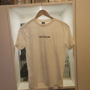 Vit t-shirt Paranoid Society Dept. - Vit t-shirt från Black Society med tryck fram och stor svart drake på ryggen. Texten 'paranoid' och 'Fear is temporary, regret is forever' ger en edgy vibe. Klassisk passform och rund hals. Perfekt för dig som gillar streetwear och coola prints.