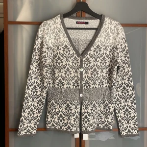 Mönstrad kofta från Indiska  - Mysig grå/vit kofta med knappar från Indiska, har en tjockare rem runt midjan för att framhäva midjan. 