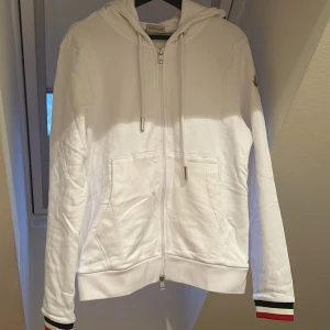 Moncler zip hoodie vit - Säljer denna Moncler zipen i storlek S. Hoodien är aldrig använd och sprillans ny, taggar samt original påse följer med. Inga defekter över huvud taget. Fråga på ifall ni har funderingar. Kan gå ner i pris vid snabb affär. 