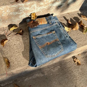 Nudie Jeans | Steady Eddie (Savage Blue) - Snygga blå jeans från Nudie Jeans med klassisk orange söm på bakfickorna och läderpatch i midjan. Jeansen har rak passform och är tillverkade i slitstarkt bomullsdenim. Perfekta för dig som gillar en tidlös och clean look. Använda minimalt och inga defekter. Priset kan diskuteras vid en snabb handel 👍