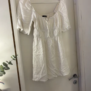 Vit kort klänning från Bikbok - Supersöt vit kort klänning från Bikbok med puffärmar och knytning vid halsen. Storlek S. 