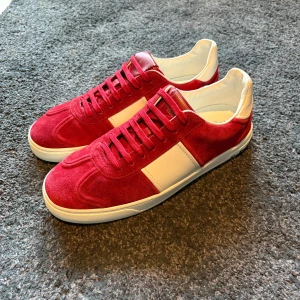 Valentino Flycrews röda - Snygga Valentino Flycrews sneakers i röd mocka med vita läderdetaljer och ikoniska nitar på hälen. Skorna är i riktigt bra skick! 9/10 alla nitar är kvar!