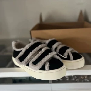 Svarta Inuikii sneakers med teddy - Intressekoll på mina svarta sneakers från Inuikii med fluffiga teddy-detaljer i vitt och breda kardborreband. Skorna har en platt vit sula och rund tå, samt är fodrade med mjukt teddy-material för extra komfort, perfekt för vintern. Skriv om intresse och för prisförslag 