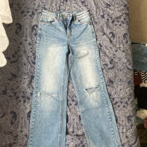 Ljusblå jeans från LAB Industries - Ljusblå jeans från LAB Industries med raka ben och slitna detaljer vid knäna. Klassisk femficksmodell i bomullsdenim med dragkedjegylf och orangea sömmar. Perfekta för en avslappnad och trendig look.