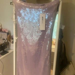 Ljuslila paljettklänning Gina Tricot XS - Superfin ljuslila tubklänning från Gina Tricot, täckt med glittriga paljetter som ger en riktigt festlig vibe. Klänningen är lång och har en rak, slim passform som sitter snyggt. Perfekt för dig som vill sticka ut med en glittrig look!