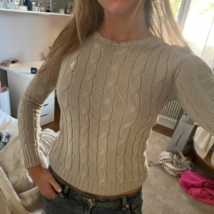 Grå kabelstickad tröja Ralph Lauren - Snygg grå kabelstickad tröja från Ralph Lauren med rund hals och långärmad passform. 