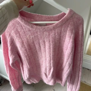 Ljusrosa stickad tröja med ribbad struktur - Supermysig ljusrosa stickad tröja med ribbad struktur och rund hals. Tröjan har långärmade ärmar och en lite loose passform, perfekt för att hålla sig varm och ändå se söt ut. Passar dig som gillar mjuka och fluffiga material.