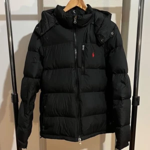 Ralph Lauren jacka - Helt ny Ralph Lauren jacka, 10/10 skick. Den är endast använd en gång och nu inser jag att den inte kommer till användning så därför säljer jag den, jackan är som ny. Det är storlek M, sitter som en vanlig M jacka. Det är svart färg på den. Riktigt varm och bekväm inför vintern, hör av er vid frågor och funderingar! Väldigt billig vinterjacka, missa inte chansen!