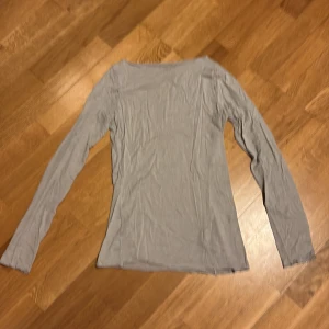 Ljusgrå långärmad topp - En enkel och stilren ljusgrå långärmad topp med rund hals. Tunn och mjuk, perfekt att matcha med jeans eller kjol. Passformen är normal och materialet känns lätt mot huden.